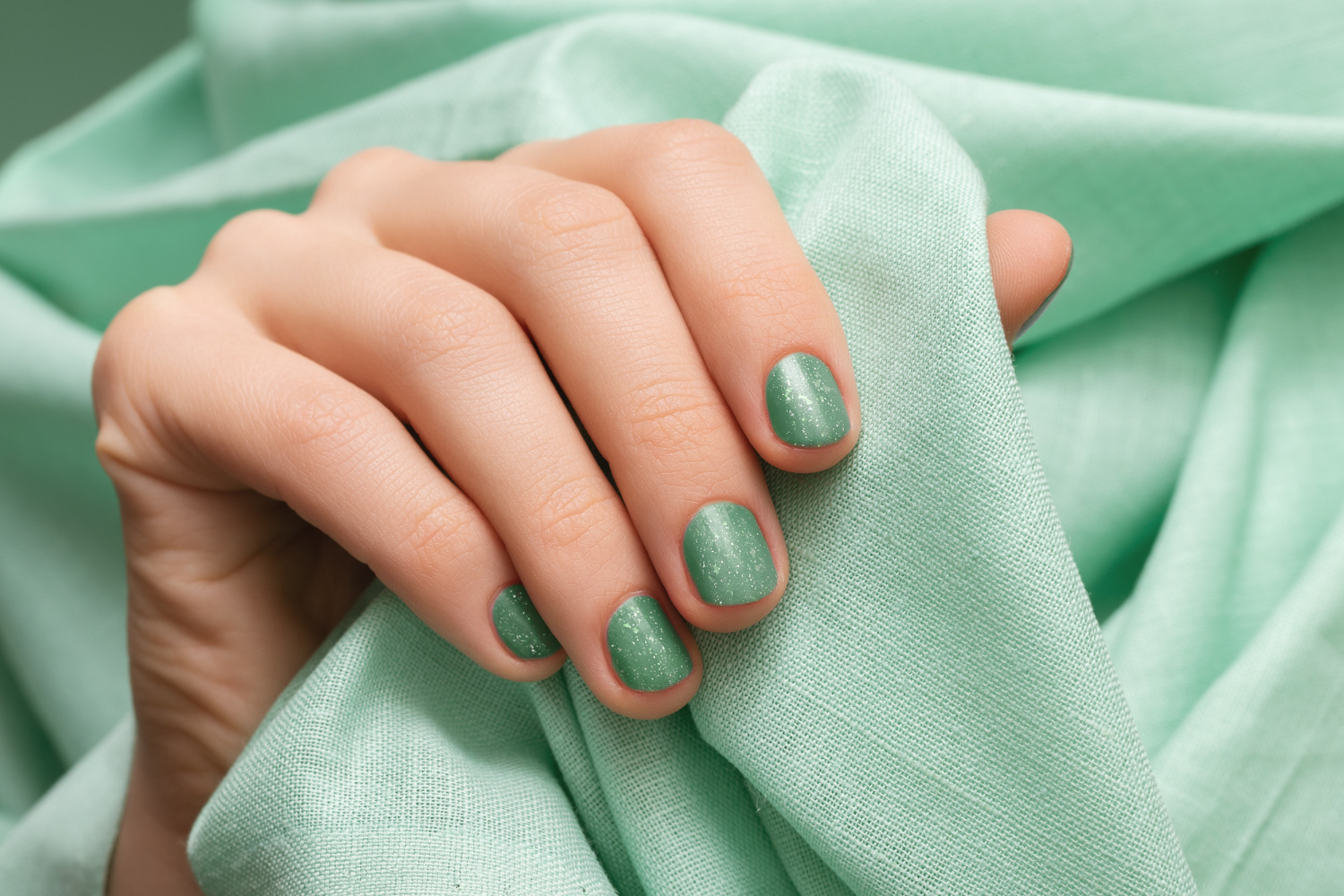 female-hand-with-green-glitter-nail-design
